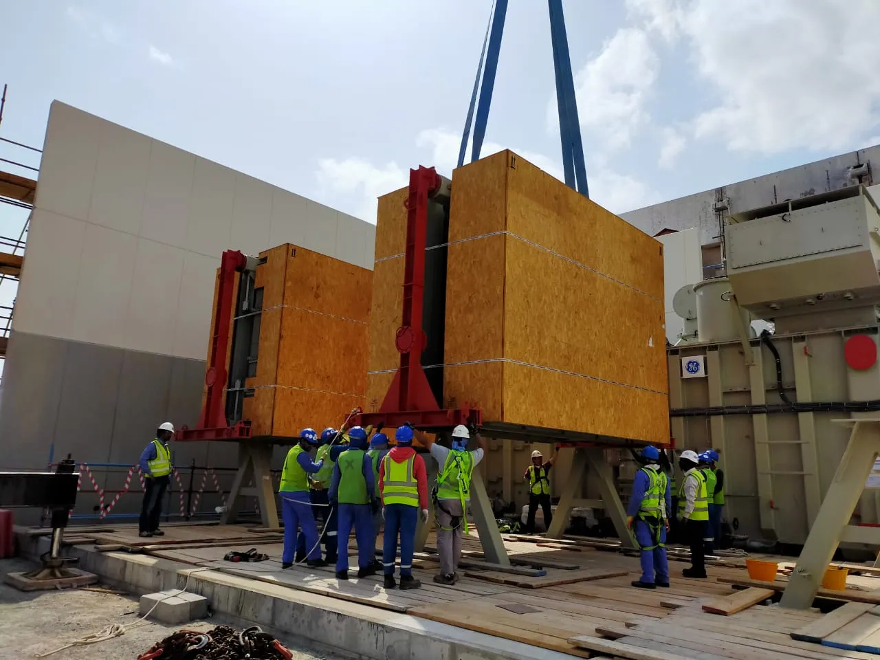 Crated power transformer being craned into a substation building